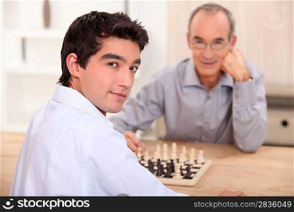 Young man playing chess with his grandfather