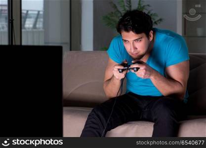 Young man playing computer games late at night