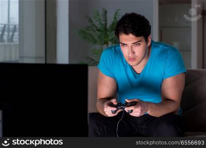 Young man playing computer games late at night