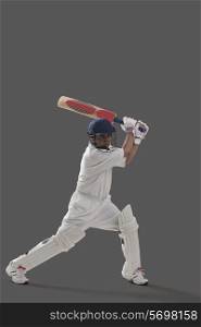 Young man playing cricket isolated over gray background