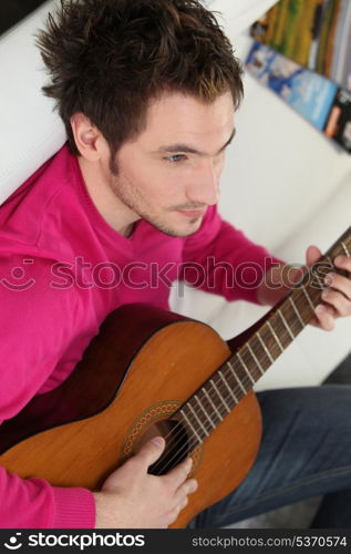Young man playing his guitar at home