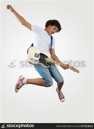 young man playing on electro guitar and jumping