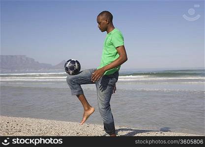 Young man playing soccer on beach