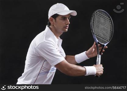 Young man playing tennis isolated over black background