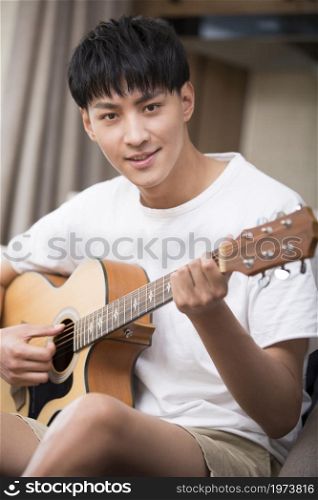 Young man playing the guitar in the living room
