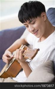 Young man playing the guitar in the living room