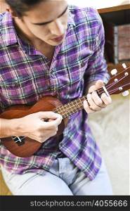 Young man playing ukulele, elevated view