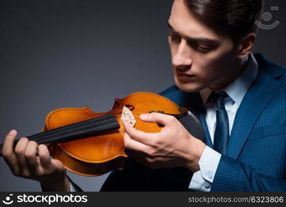 Young man playing violin in dark room