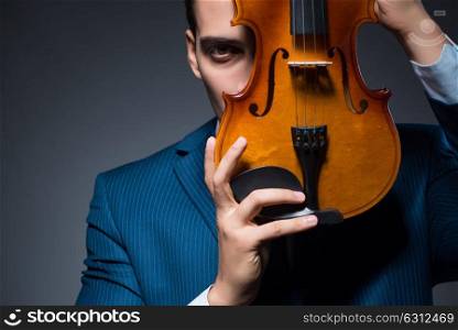 Young man playing violin in dark room. The young man playing violin in dark room