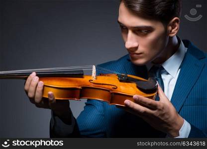 Young man playing violin in dark room. The young man playing violin in dark room