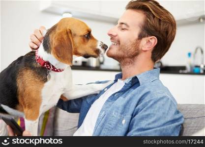Young Man Playing With Pet Dog At Home