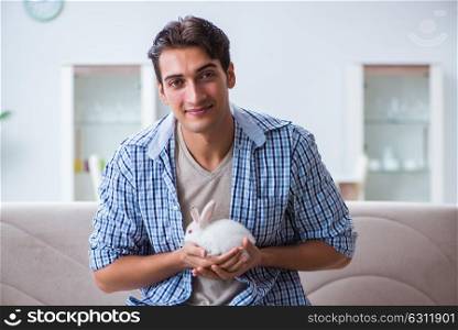 Young man playing with pet rabbit at home. The young man playing with pet rabbit at home