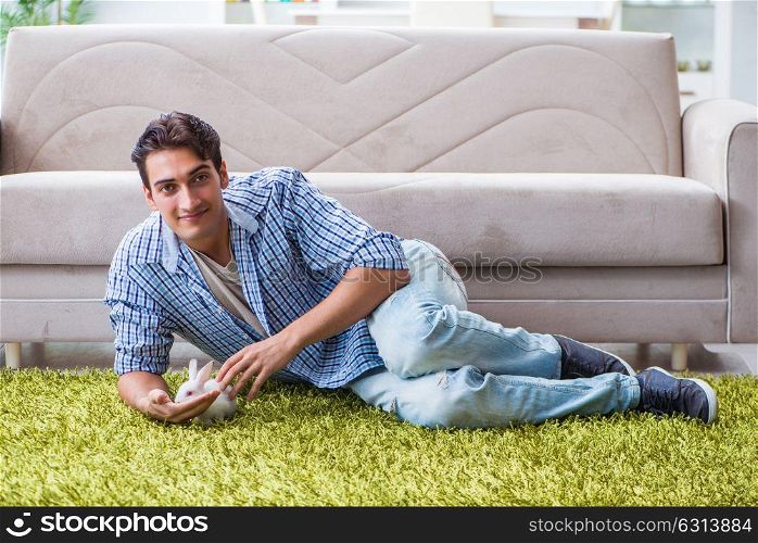 Young man playing with pet rabbit at home. The young man playing with pet rabbit at home