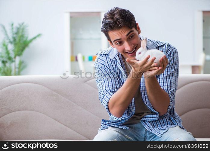 Young man playing with pet rabbit at home