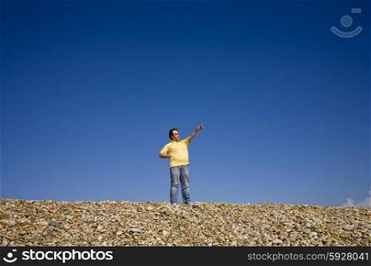 young man pointing at the beach with blue sky