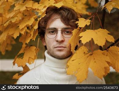 young man posing autumn leaves