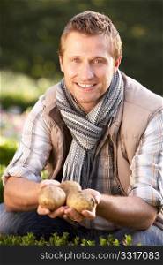 Young man posing with potatoes in garden