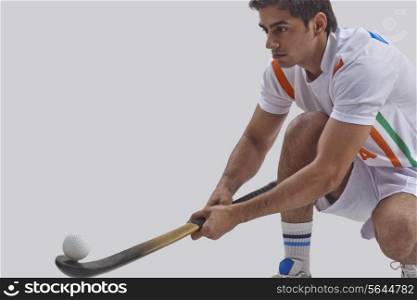 Young man practicing hockey against gray background