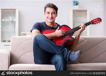 Young man practicing playing guitar at home