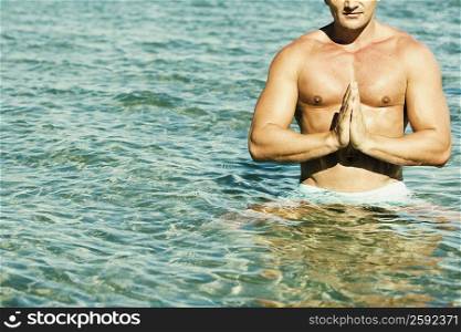 Young man practicing yoga in water