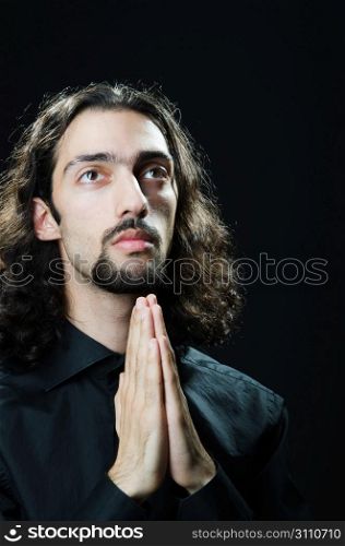 Young man praying in darkness