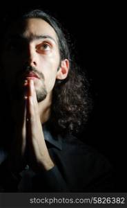 Young man praying in darkness