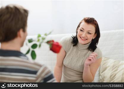 Young man presenting red rose to girlfriend