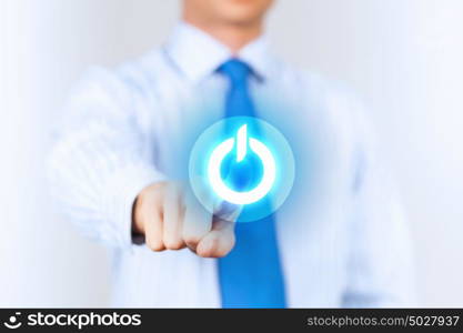 Young man press the power button. Young man in a light shirt and blue tie press the power button. Shallow depth of field.