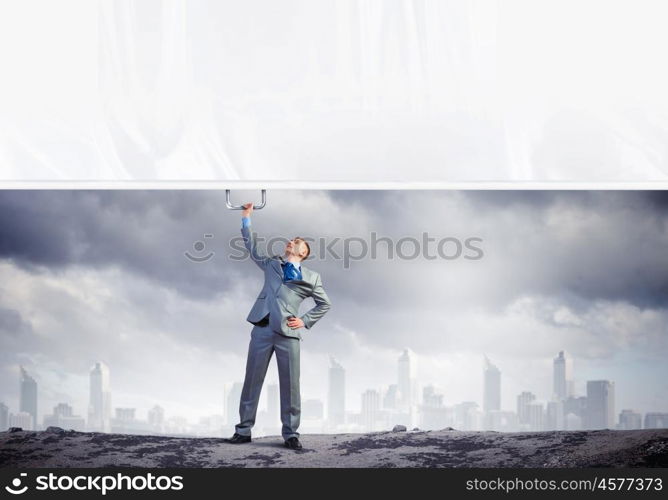 Young man pulling banner. Image of young businessman pulling blank banner from above