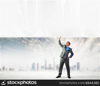Young man pulling banner. Image of young businessman pulling blank banner from above