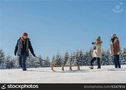 Young man pulling snow sledge winter countryside female girlfriends
