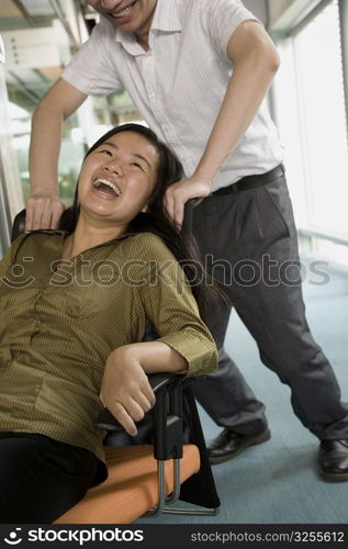 Young man pushing a young woman sitting in a chair