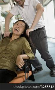 Young man pushing a young woman sitting in a chair