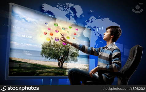 Young man pushing icon. Young man in armchair pushing icon on media screen