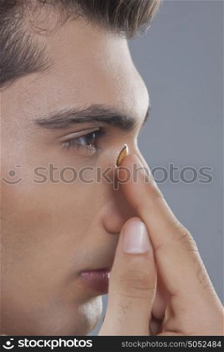 Young man putting contact lens