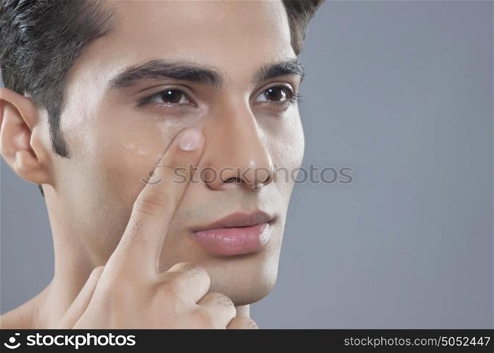 Young man putting on anti wrinkle gel