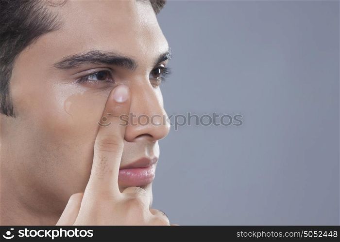Young man putting on anti wrinkle gel