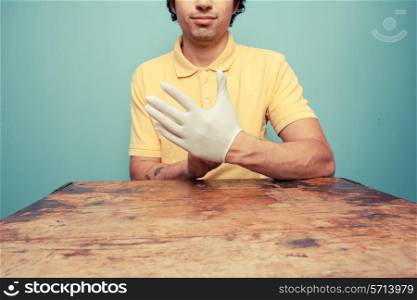 Young man putting on latex glove