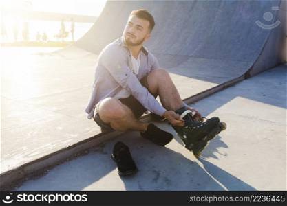 young man putting rollerskates skate park