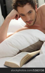 Young man reading a book in bed