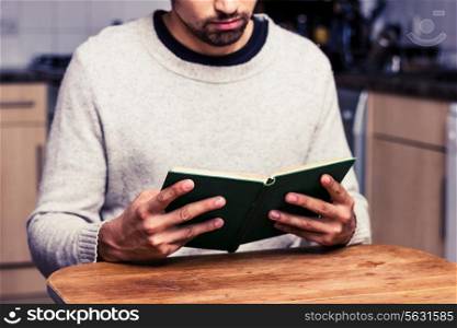 Young man reading a book in the kitchen
