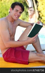 Young man reading a book on the beach