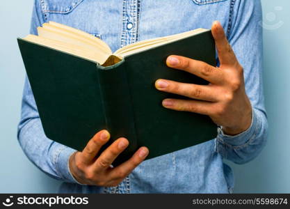 Young man reading big book