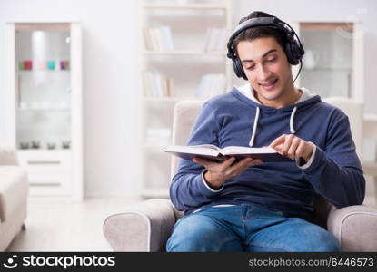 Young man reading book and listening to audio book