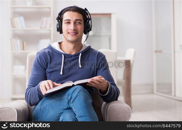 Young man reading book and listening to audio book