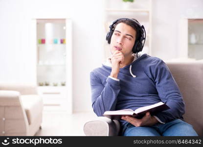 Young man reading book and listening to audio book