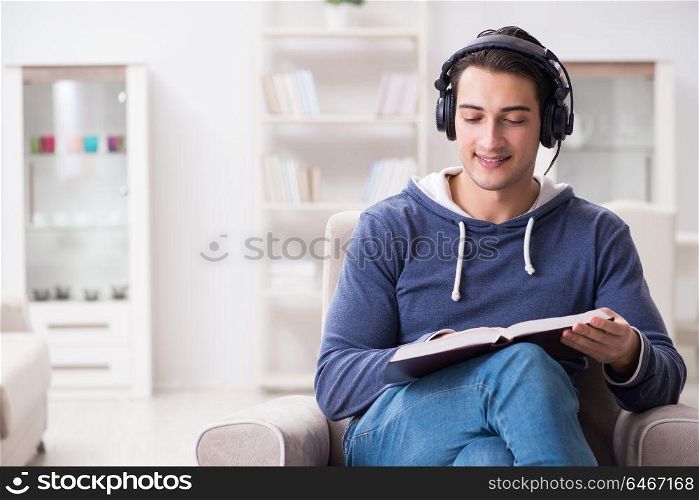 Young man reading book and listening to audio book