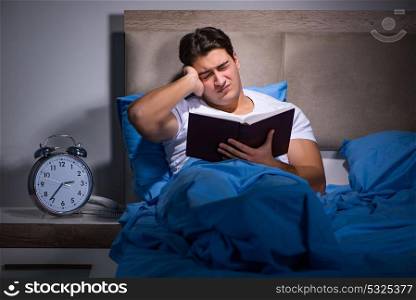 Young man reading book in bed