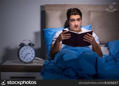 Young man reading book in bed