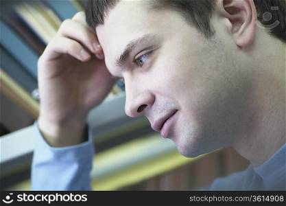 Young man reading in library leaning on elbow